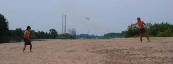 Frisbee-Spielen auf dem Strand, im Hintergrund das Kraftwerk Polaniec